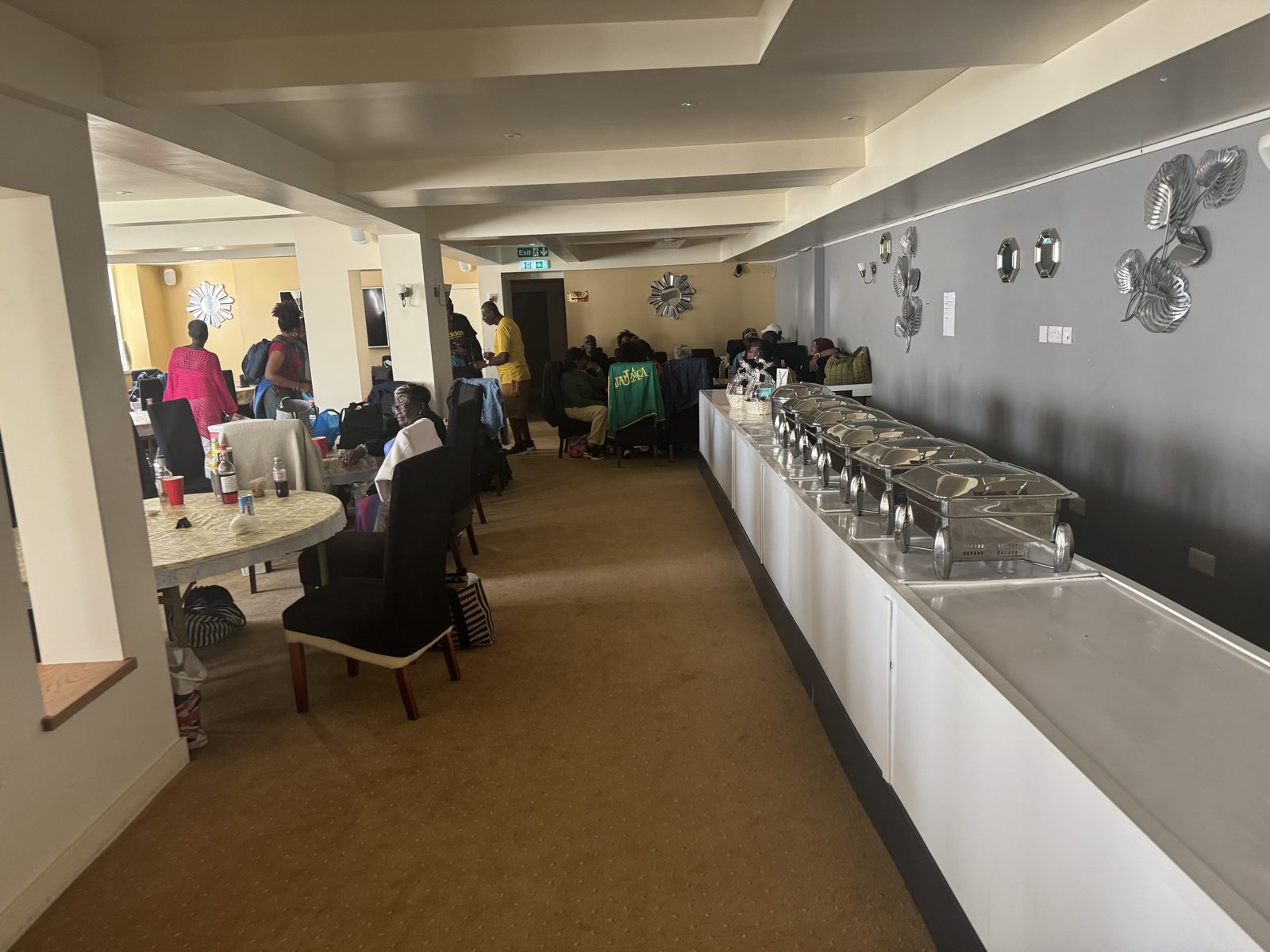 A function room with guests at tables and a long buffet counter of serving dishes